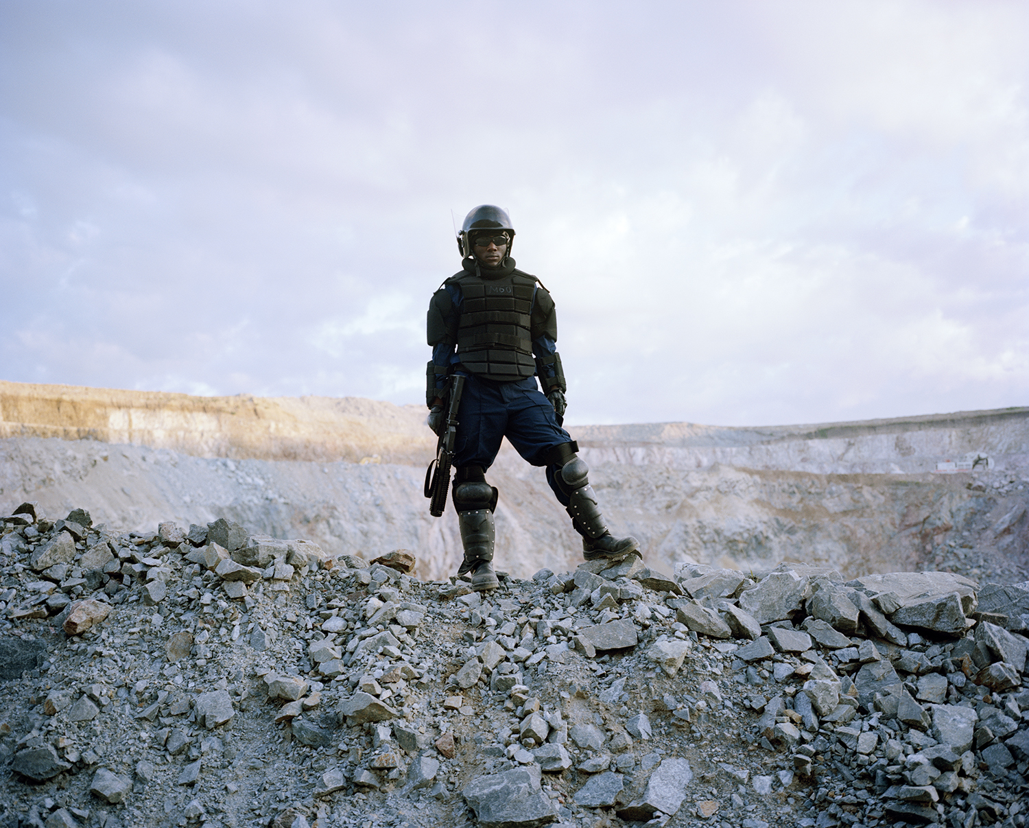 untitled # IV, mine security, north mara mine, tanzania-from the story ‘intruders’ David Chancellor ‘Intruders’ The seven villages around the north Mara gold mine, amongst the poorest and most underdeveloped in Tanzania, are located in the north western corner of the country, 30 kilometres from the Kenyan border and belong mostly to the Kuria people, who were traditionally cattle farmers. Colonial records described them as ‘unruly and backward’. They became notorious for cattle rustling and inter-clan fighting and joined the Tanzanian army in huge numbers. As they resisted the collective policies of the 1970’s the area became an opposition stronghold, neglected by the government and lacking in basic services. Despite the regions isolation, its gold wealth has been known since the 19th Century, when small scale mining began. Today the region is a key contributor to Tanzania’s gold sector, which has emerged as the country’s most valuable export, accounting for 40% of export earnings. On average 800 villagers and migrants enter north Mara mine illegally every day to scrounge for rock. They have borrowed an English word to describe themselves: ‘intruders’. The word has entered the Swahili language, with no negative connotation, as the name of a new occupation that can produce money and even wealth. As gold prices continue to rise and the mine becomes more valuable, the conflict intensifies. The massive piles of waste rock have become the only real source of income for the villagers, who have largely abandoned farming and have little hope of wage employment. And the rising price of gold has drawn a rush of newcomers from across East Africa. As long as Tanzanians are forced to choose between dying for living and the potential wealth that they can gain by invading the mine, the bloodshed is likely to continue.. David Chancellor.