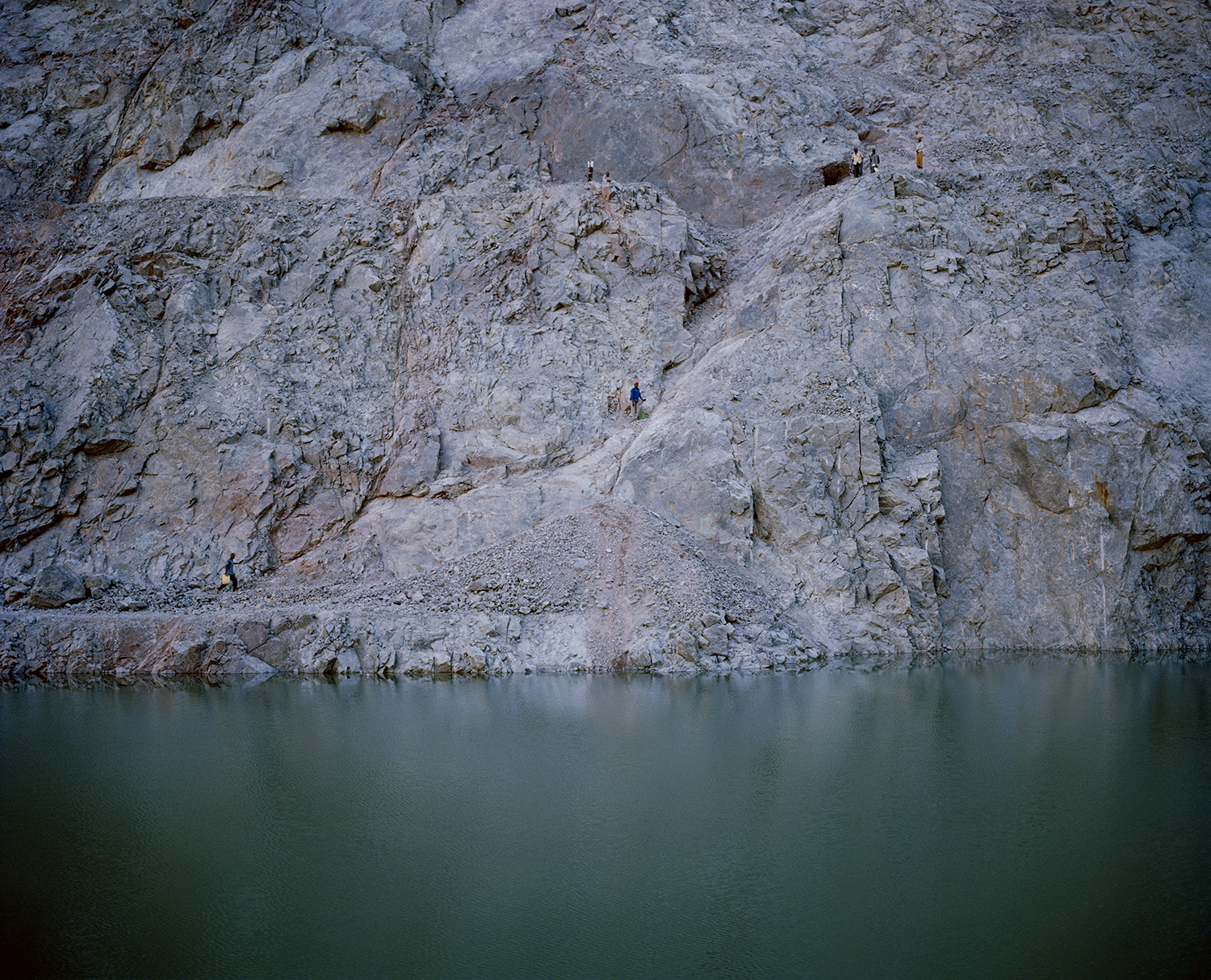DC 6557.41 untitled # IV, mine security, north mara mine, tanzania-from the story ‘intruders’ David Chancellor ‘Intruders’ The seven villages around the north Mara gold mine, amongst the poorest and most underdeveloped in Tanzania, are located in the north western corner of the country, 30 kilometres from the Kenyan border and belong mostly to the Kuria people, who were traditionally cattle farmers. Colonial records described them as ‘unruly and backward’. They became notorious for cattle rustling and inter-clan fighting and joined the Tanzanian army in huge numbers. As they resisted the collective policies of the 1970’s the area became an opposition stronghold, neglected by the government and lacking in basic services. Despite the regions isolation, its gold wealth has been known since the 19th Century, when small scale mining began. Today the region is a key contributor to Tanzania’s gold sector, which has emerged as the country’s most valuable export, accounting for 40% of export earnings. On average 800 villagers and migrants enter north Mara mine illegally every day to scrounge for rock. They have borrowed an English word to describe themselves: ‘intruders’. The word has entered the Swahili language, with no negative connotation, as the name of a new occupation that can produce money and even wealth. As gold prices continue to rise and the mine becomes more valuable, the conflict intensifies. The massive piles of waste rock have become the only real source of income for the villagers, who have largely abandoned farming and have little hope of wage employment. And the rising price of gold has drawn a rush of newcomers from across East Africa. As long as Tanzanians are forced to choose between dying for living and the potential wealth that they can gain by invading the mine, the bloodshed is likely to continue.. David Chancellor.